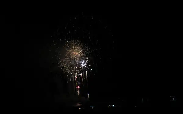 זיקוקים מעל הים בלילה עם אורות של וילה ובריכה בחזית